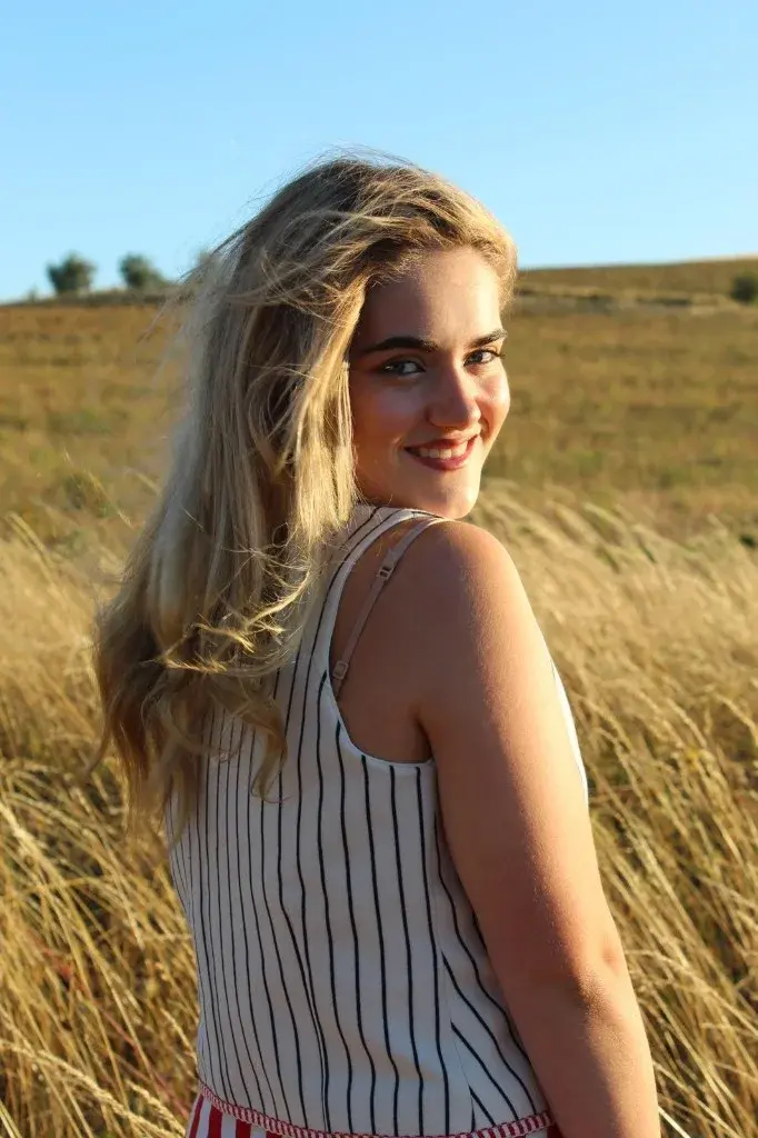Indiana smiling over her shoulder in a golden field.